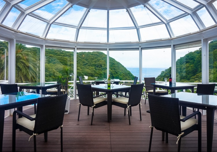 海と緑を一望する絶景レストラン。明るい陽光が差し込む空間で、心を込めたお迎えを。