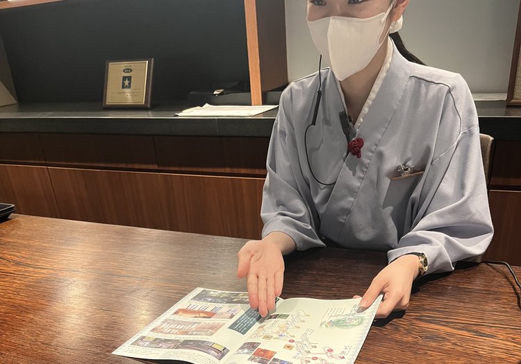 館内マップを広げて過ごし方をご案内。周辺の楽しみ方までお伝えする役割です。
