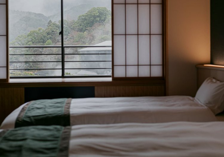 山々の緑を望むベッドルーム。心地よいご滞在を客室の準備とご案内で支えます。