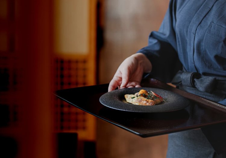 作務衣に身を包み、心を込めてお料理をお運びします。距離の近いおもてなしが魅力です。