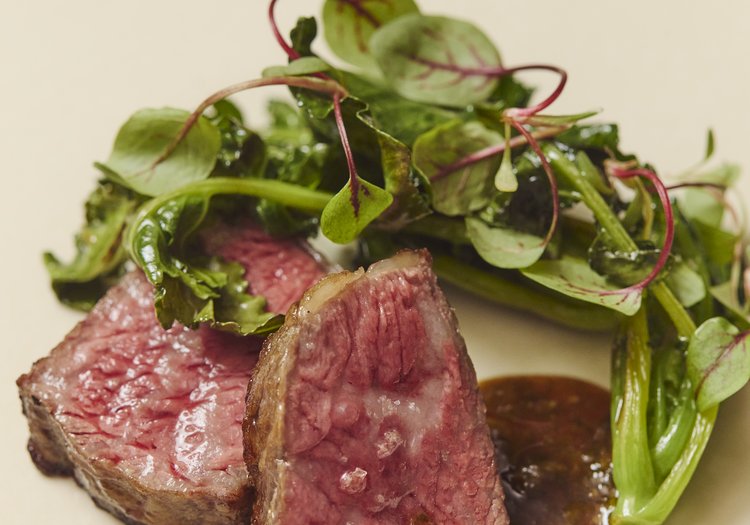火入れにこだわった肉料理。自家製のソースと瑞々しい葉野菜を添えて提供する一皿です