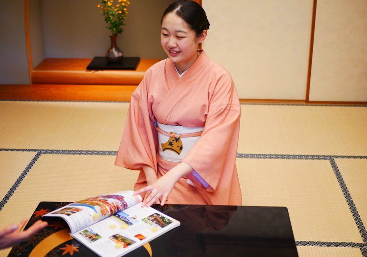 観光案内の冊子を手にご案内する仲居。嵐山の楽しみ方もお客様にお伝えします