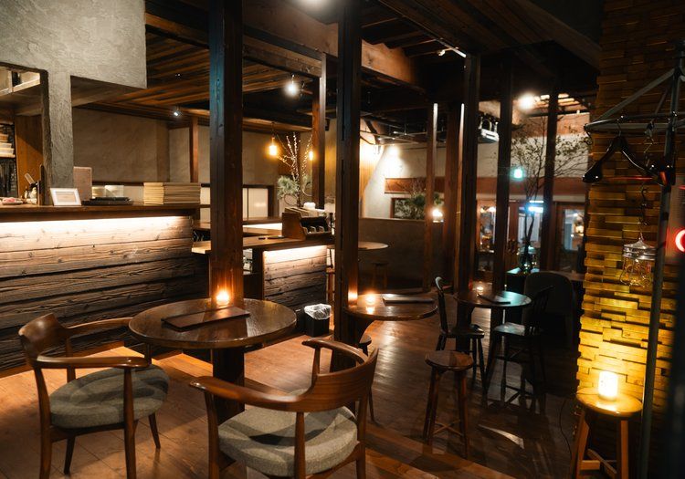 夜のカフェダイニング。キャンドルの灯るテーブル席で、宿泊ゲストや地域の方を迎えます。