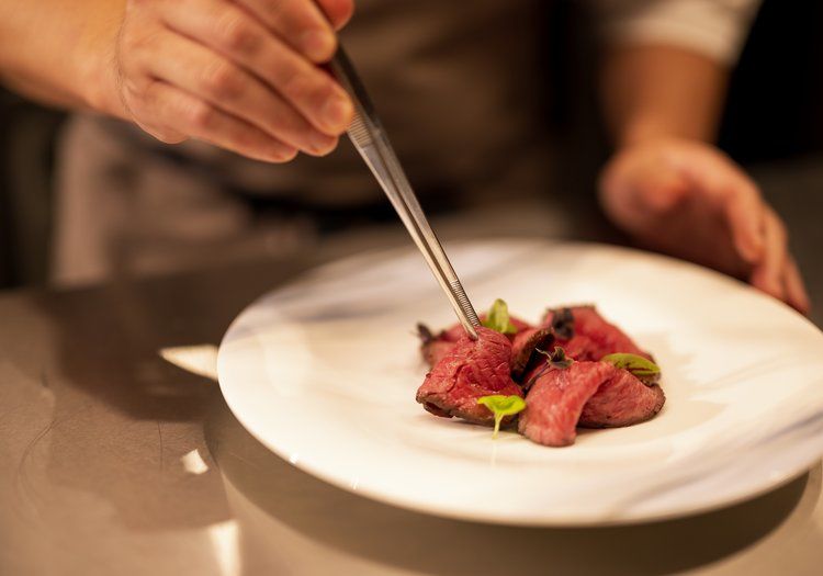 一皿ずつ丁寧に盛り付けを仕上げる手元。料理の美しさまでこだわる姿勢が息づいています。