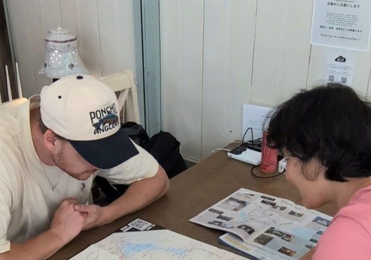 地図を広げて観光のご相談に対応。必要なときに頼れる距離感で、旅の計画をお手伝いします。