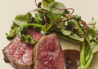 火入れにこだわった肉料理。自家製のソースと瑞々しい葉野菜を添えて提供する一皿です